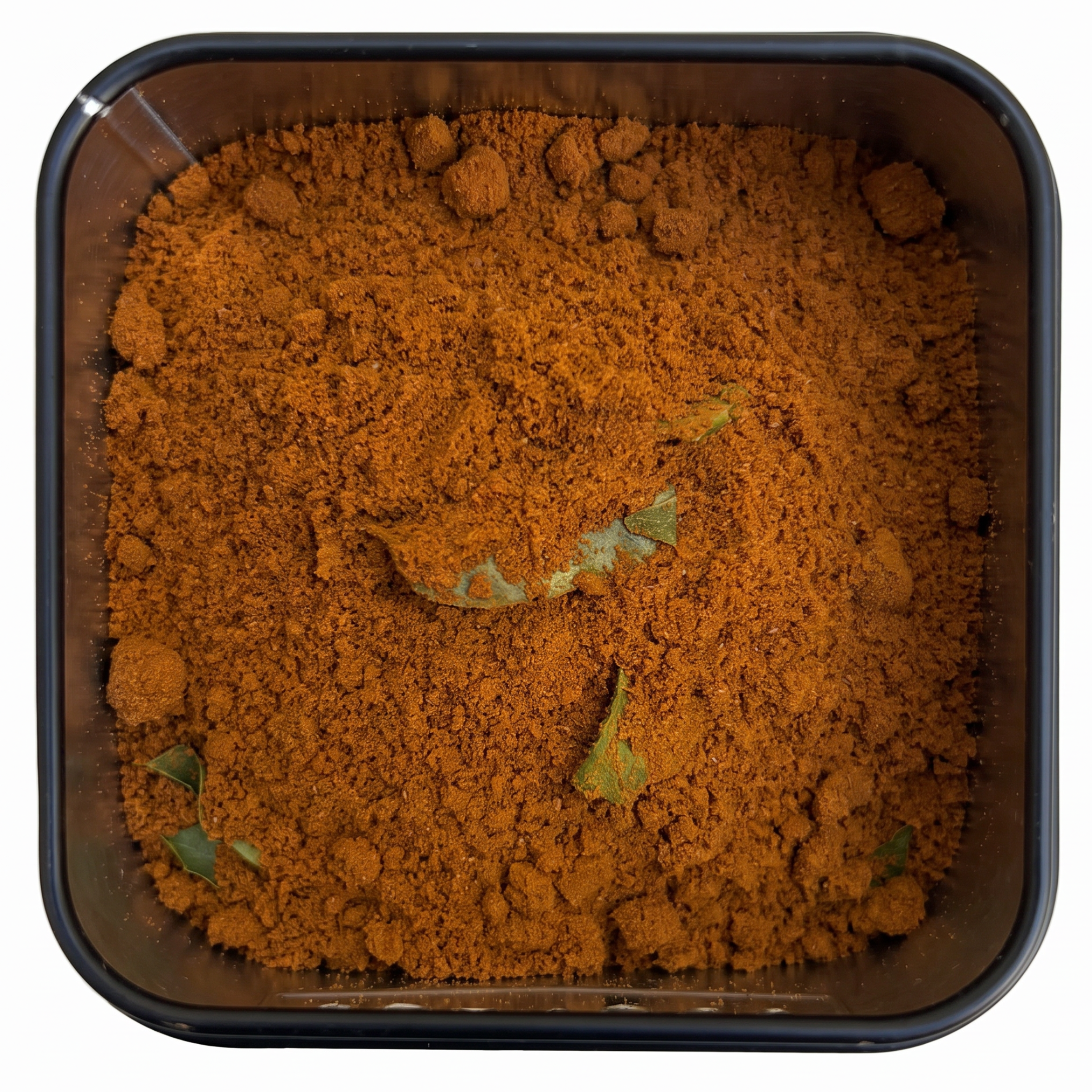 Jaffna Curry, kräftig rot-braunes Currypulver mit grünen Curryblättern, in schwarzer Gewürzdose