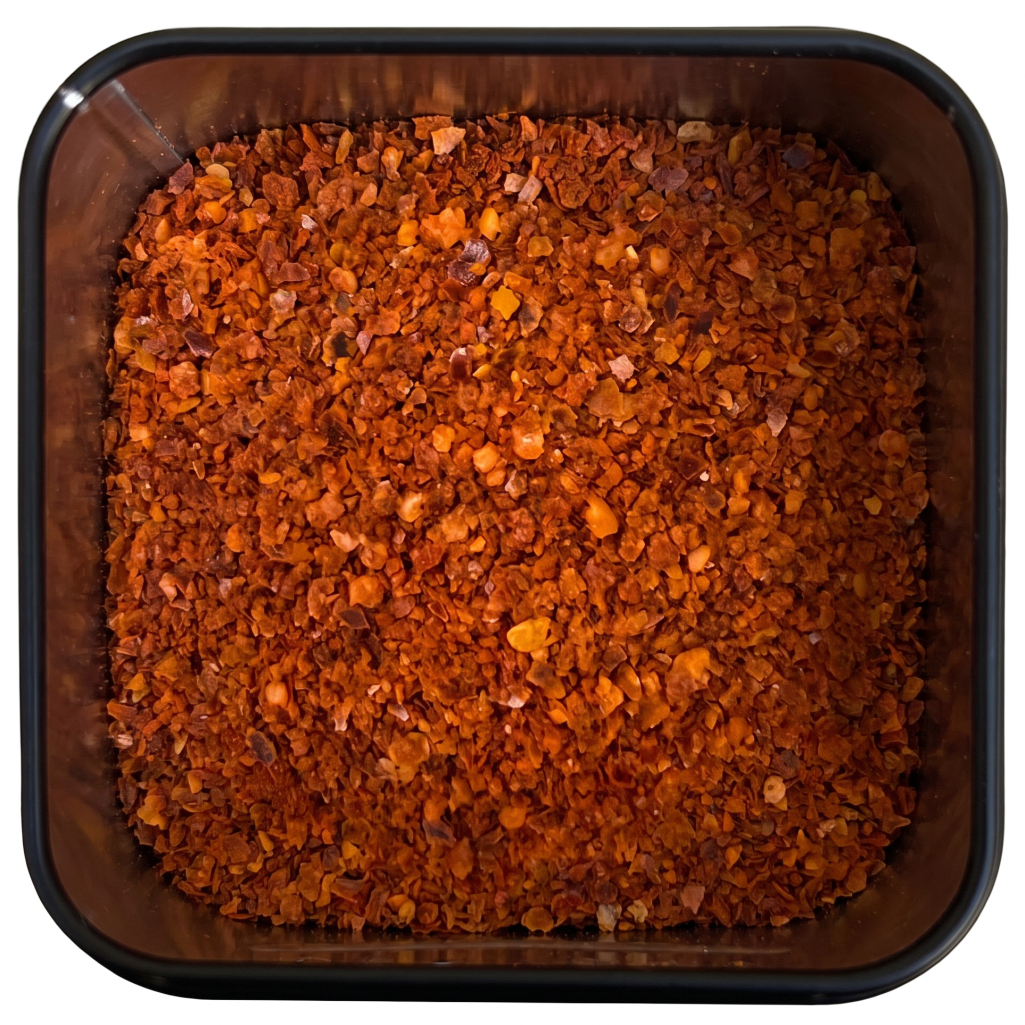 Chiliflocken ohne Saat, grobe orange-rote Flocken unterschiedlicher Größe, in schwarzer Gewürzdose, scharf-würzig.