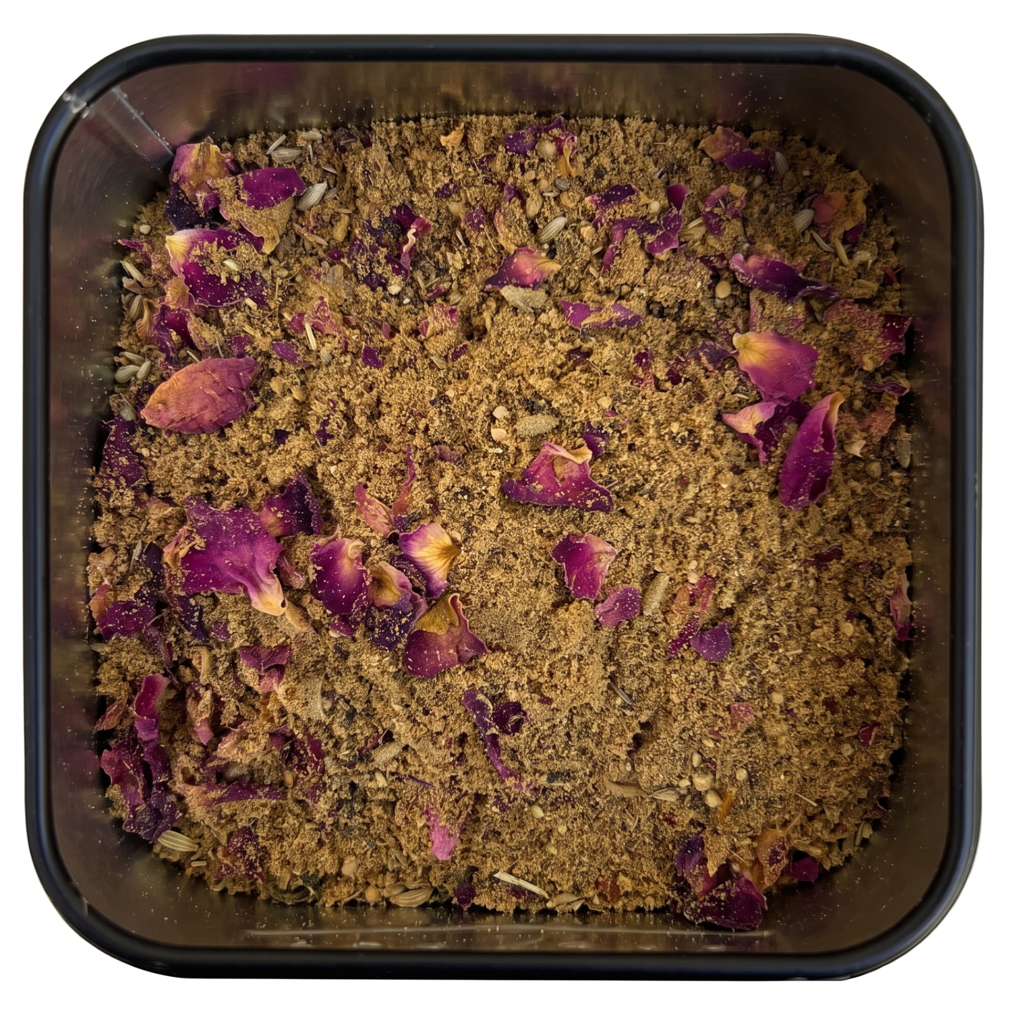 Ras el Hanout, braunes Gewürzpulver mit violetten Rosenblütenblättern, in schwarzer Gewürzdose