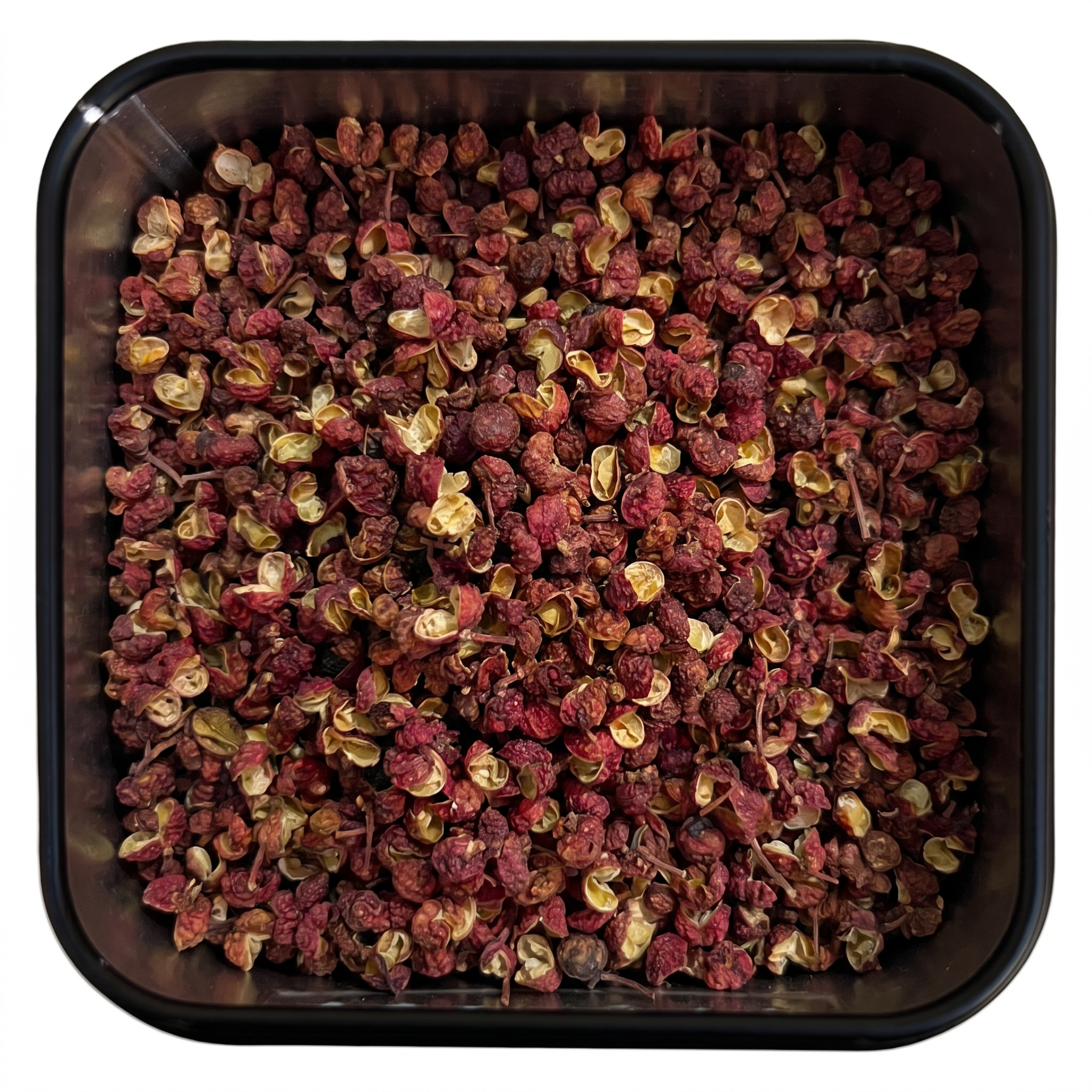 Bio Szechuanpfeffer, getrocknete rotbraune Beeren mit geöffneten hellen Schalen, in schwarzer Gewürzdose, zitronig-prickelnd.