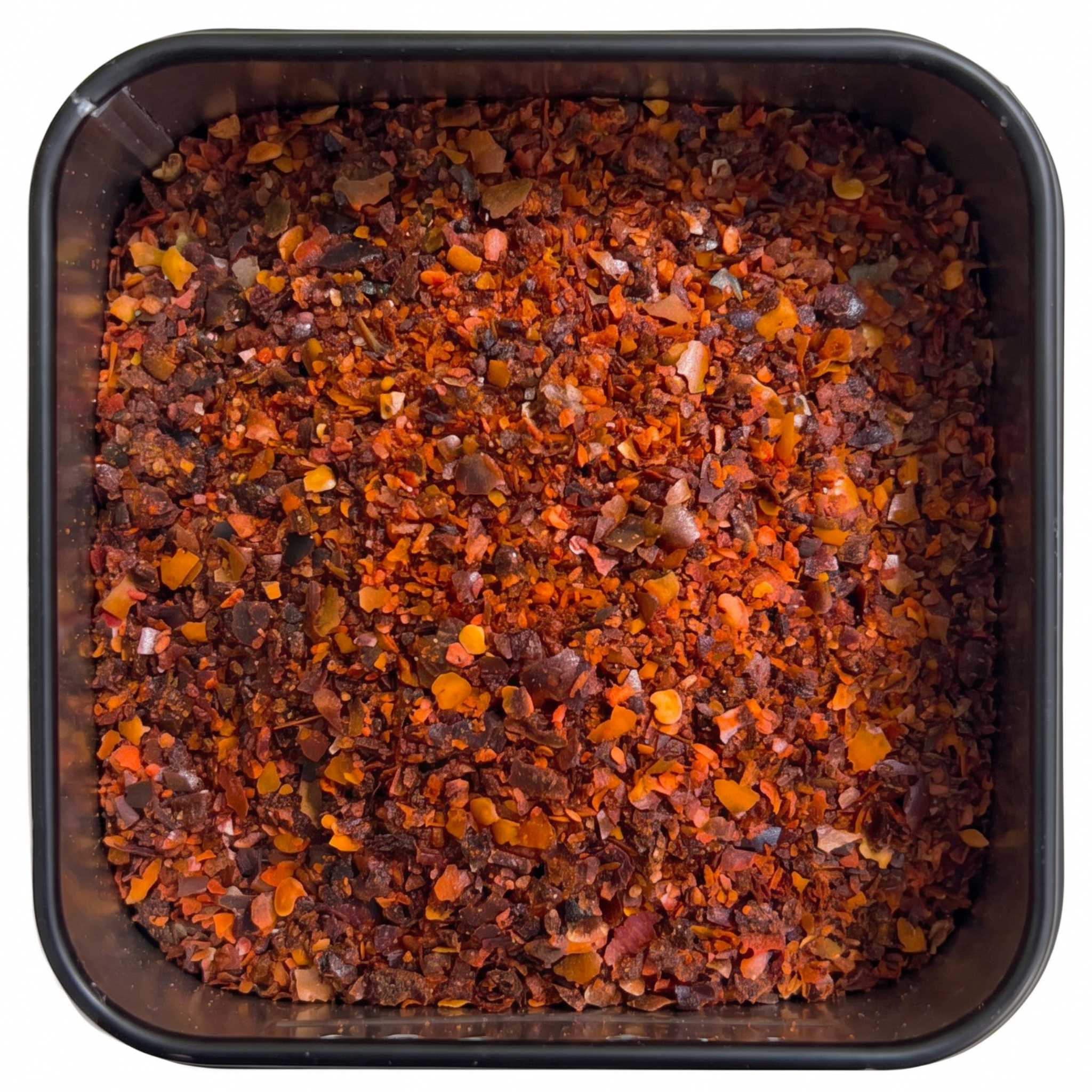 Pul Biber, grobe rot-orange bis dunkelrote Chiliflocken in unterschiedlicher Größe, in schwarzer Gewürzdose, scharf-fruchtig.